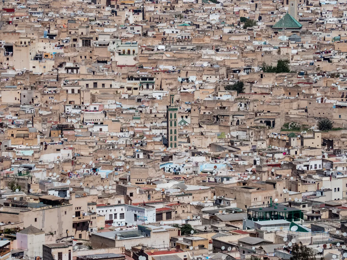 A dense old city of sand-colored rooftops stretching to the horizon, a minaret rising from the middle